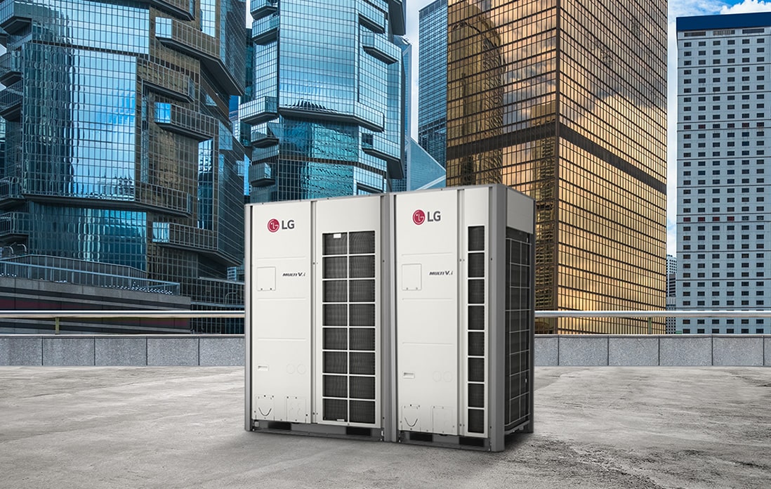 Two LG MULTI V i units stand side by side on a rooftop, front-facing view, against a backdrop of towering skyscrapers cloaked in the glass.	