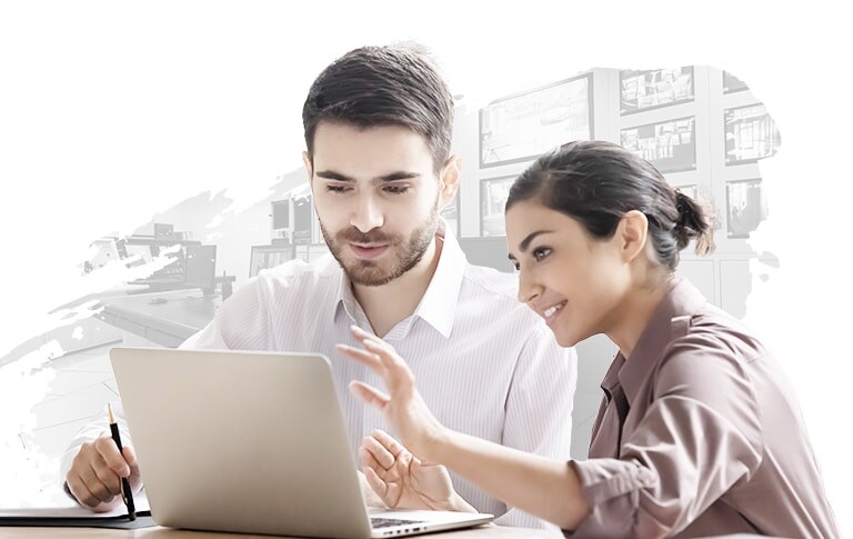 A man and a woman are seated at a desk, collaboratively working while viewing a laptop screen. The background showcases a stylized, abstract design, reflecting a modern, tech-savvy environment.