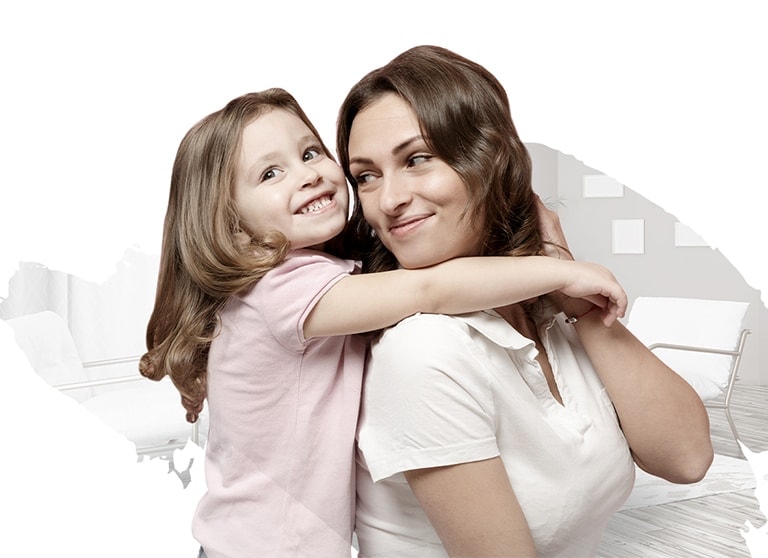 A mother and her daughter are hugging each other, wearing big smiles on their faces.