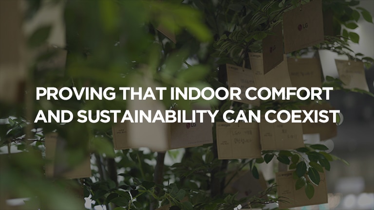 A message of indoor comfort and sustainability's coexistence, set against a green leaf backdrop with brown paper notes hanging on it.