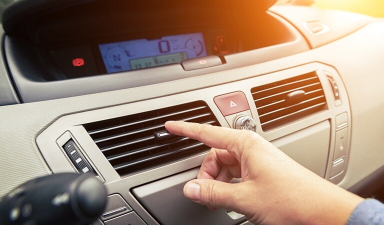 A person turning on the car airconditioner.