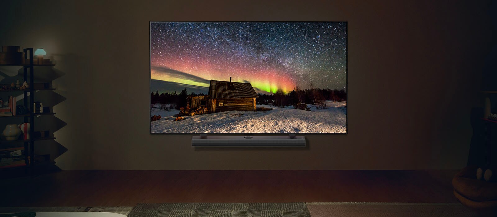 LG TV i LG Soundbar w nowoczesnej przestrzeni nocnej. Obraz zorzy polarnej wyświetlany jest z idealnym poziomem jasności.