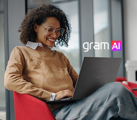 Das Bild zeigt eine lächelnde Frau, die in einer modernen, gemütlichen Umgebung an einem Laptop sitzt. Der Text lautet: „Dein eigener KI-Sekretär“ neben dem „gram AI“-Logo, das die KI-gestützten Assistenzfunktionen des Geräts hervorhebt.