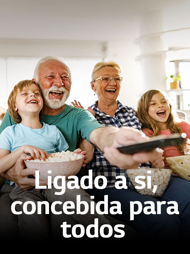 Uma família está sentada a rir enquanto o avô aponta o controlo remoto para o exterior.