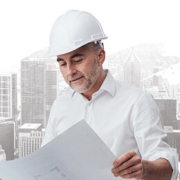 Projetista de HVAC com um capacete de segurança a olhar para um plano.