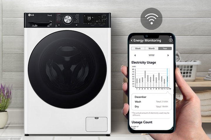 A máquina de lavar está na lavandaria. A mão segura o telemóvel que mostra o ecrã para a câmara e o ecrã mostra a informação da manutenção e uso de energia com um símbolo Wi-Fi acima do ecrã.