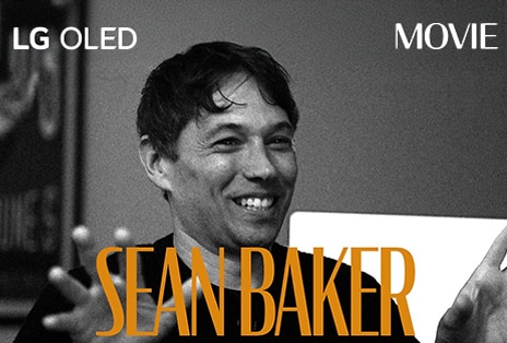 صورة ثابتة بالأبيض والأسود من مقابلة مع Sean Baker. ويظهر اسمه بأحرف برتقالية غامقة في الجزء السفلي من الإطار. توجد عبارة LG OLED في الزاوية اليسرى العليا، وكلمة فيلم في الزاوية اليمنى العليا.