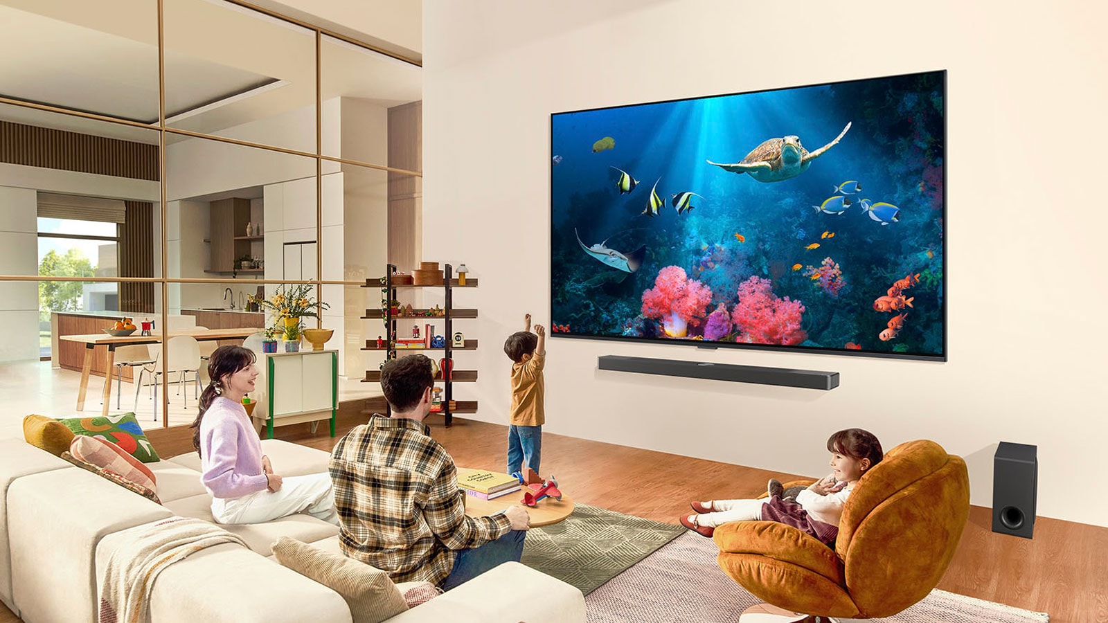 يظهر عائلة في غرفة معيشة مع تلفزيون LG TV كبير جدًا معلق على الحائط، مع مشهد للمحيط يتضمن مرجانًا وسلحفاة على الشاشة.