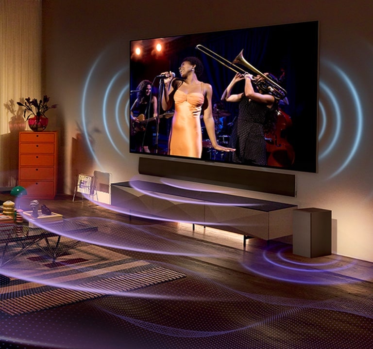 An image of an LG OLED TV in a room showing a music concert. Blue curved lines depicting TV sound and purple curved lines expressing Soundbar sound fill the space.