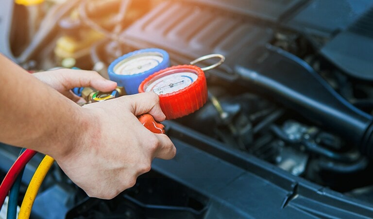 A person checking the car refrigerant pressure