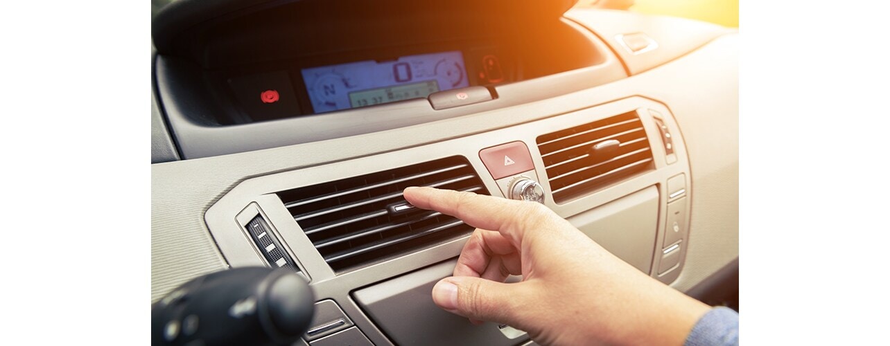 A person turning on the car airconditioner.