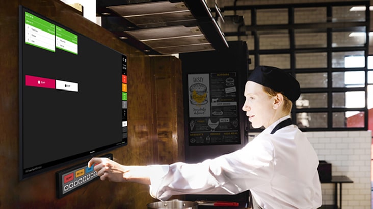 A kitchen staff member is checking order details on the kitchen display.