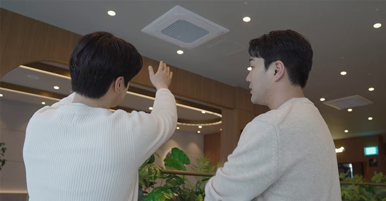 Two men are talking while looking at the air conditioner.