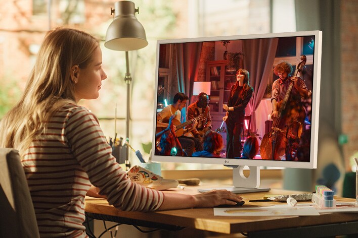 Stylish single woman sitting at her desk, enjoying streaming content on the LG MyView Smart Monitor without a PC.