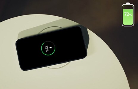 A smartphone is being charged on top of a wireless charger on an Aero Furniture.