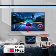 An LG SIGNATURE OLED M4 mounted on a living room wall and a laptop on a table in front displaying the same car racing game. A close-up of a Zero Connect Box on a smaller table, with a console connected underneath and a red Wi-Fi signal and red beam emitting towards the TV. The words "hassle FREE" in the bottom left corner.