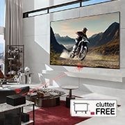 An LG SIGNATURE OLED M4 within an angled perspective mounted on the wall of a bright, modern living room. A Zero Connect Box on a table in front, and a red Wi-Fi signal and red beam emitting towards the TV. The words "clutter FREE" in the bottom right corner.