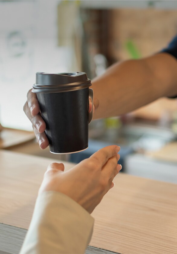 The screen zooms in to show the customer and the café owner exchanging ordered drinks in a cafe.