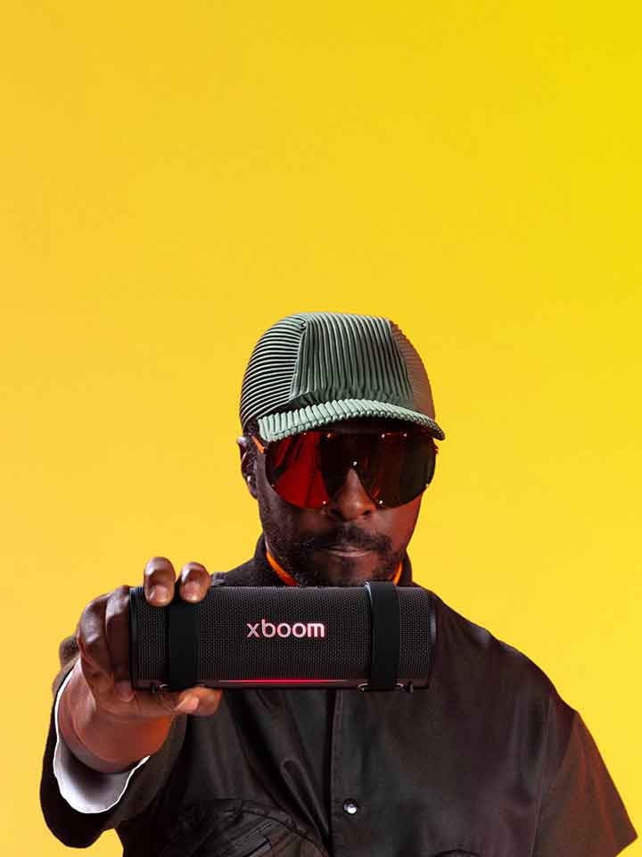 will.i.am ใส่ชุดขาวและแว่นกันแดด กำลังถือ xboom Bounce ใกล้กับใบหน้าของเขา