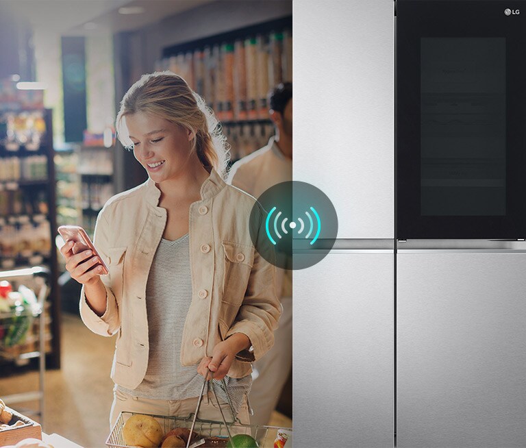 หญิงสาวถือโทรศัพท์และตะกร้าในร้านค้า ตู้เย็น LG พร้อมสัญญาณ Wi-Fi