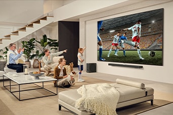 Devasa ekranda heyecan verici bir futbol maçını izleyen aile, LG Ultra Büyük TV’nin etrafında toplanmış.