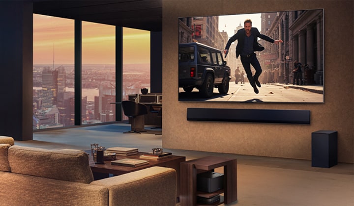 Yüksek bir apartmanda lüks ve şık bir daire. LG Tamamen Kablosuz TV ve Soundbar duvara monte edilmiş. TV ekranında bir film oynuyor. Görünürde kablo yok. Zero Connect Box, yan sehpanın altına gizlenmiş. 