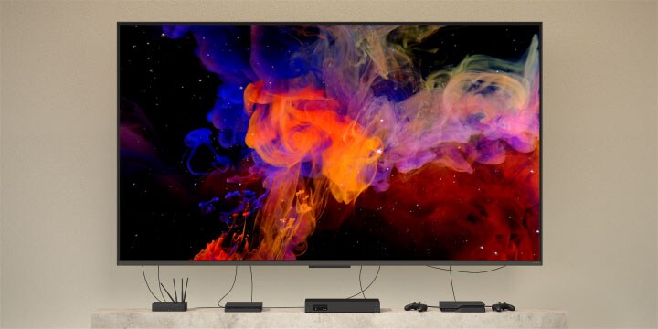 Birden fazla cihaza bağlı duvara monteli QNED9M’nin yakından görünümü. Kablolar ve cihazlar yavaşça kaybolur ve görüntüde sadece duvara monteli QNED9M kalır. Yavaş yavaş uzaklaşarak modern bir eve monte edilmiş QNED9M’yi gösterir. Zero Connect Box kahve sehpasının üzerinde duruyor. 