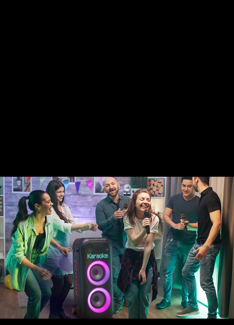 Oturma odasında karaokenin keyfini çıkaran insanlar gösteriliyor.