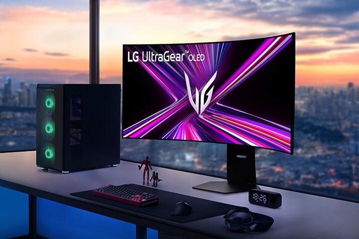 日落時分，遠眺城市景觀的遊戲桌上擺放著 LG UltraGear OLED 顯示器與電腦。	