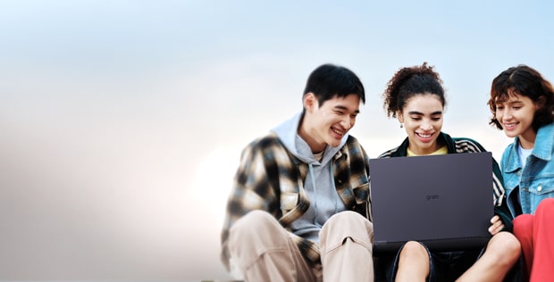 3 young people sat around LG gram laptop