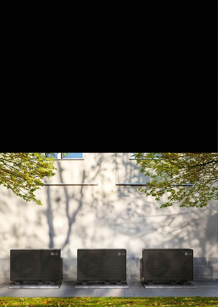A black LG THERMA V product is placed in the garden of the house and a woman with a box is passing by in front of it.