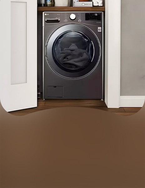 Front view of LG washing machine installed in a closet-style space with open doors and laundry inside the drum