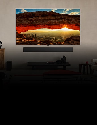 Wall-mounted OLED evo TV displaying vivid sunset through red rock arch in modern living room.
