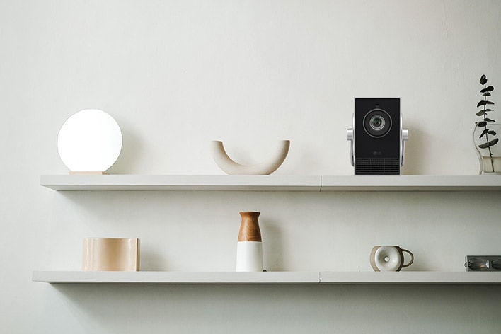 It shows the Cinebeam Q projector elegantly displayed on a shelf, blending in with various decorative items.