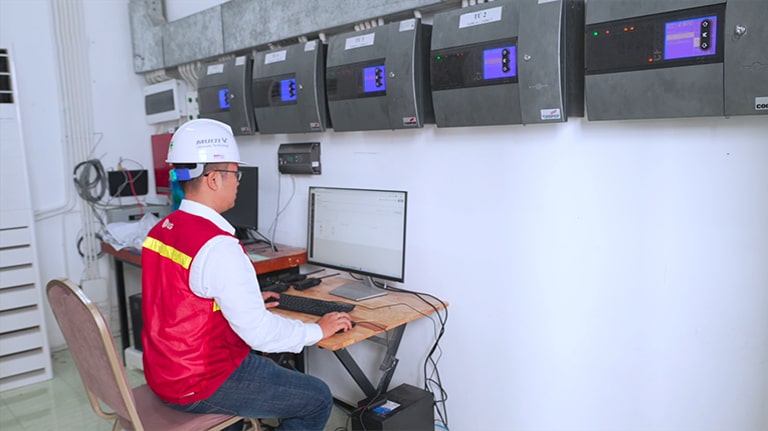 An employee is standing in front of a computer, monitoring