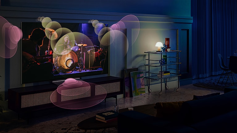 People sit on a couch watching a concert with bubbles depicting surround sound around them.