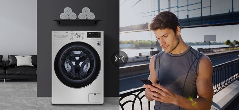 A man outdoors is checking the condition of a washing machine at home through a mobile phone app.