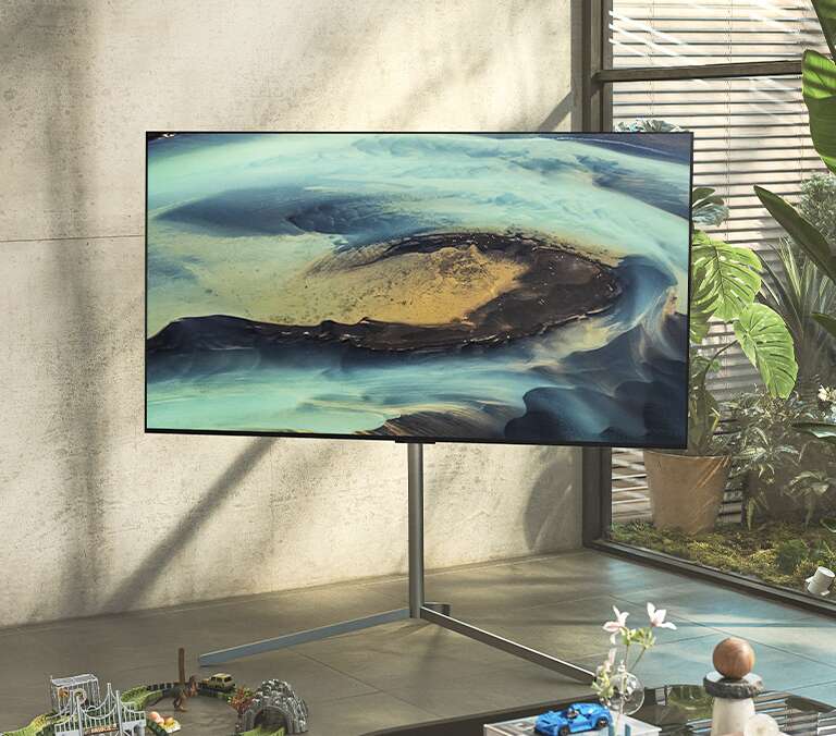 Gallery Stand seen placed in the corner of a bright and sunny room with a mounted LG TV, giving the space an elegant touch.