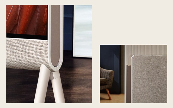 LG OLED Posé's bottom corner is seen closeup from the front focusing on the fabric, with wood flooring in the background.   The fabric of LG OLED Posé's Media Shelf and LG Objet logo are seen closeup with an armchair in the background.