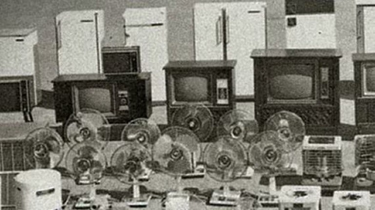 Rows of electronics, including fridges, TVs, fans, and more are on display in black and white.