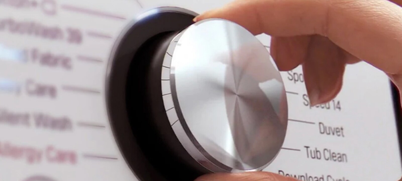 Image of the hand with a controller of white lg washing machine.