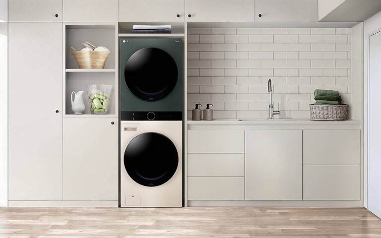 A modern laundry area featuring an LG WashTower in a sleek cabinet setup, with white cabinets, subway tile backsplash, and a countertop with a sink and a basket of folded towels.