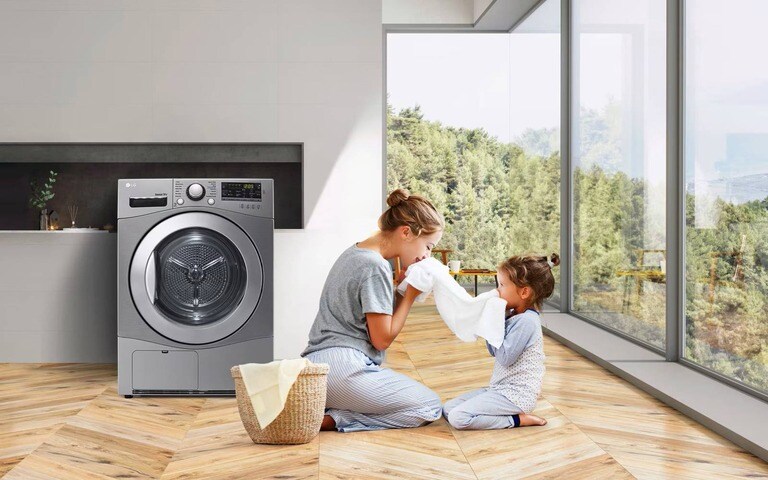 A mother and daughter enjoying fresh laundry from an LG washing machine in a bright, natural-lit room, emphasising gentle fabric care.