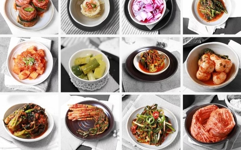 12 bowls of various kimchi and pickled vegetables, showcasing a colourful assortment of Korean side dishes.