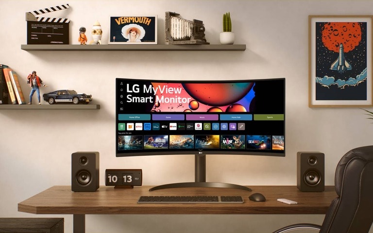 LG Smart Monitor on a modern desk with speakers and a clock. The background includes shelves with decor and wall art, creating a stylish workspace.