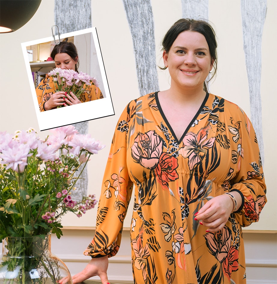 It's an image of a woman looking straight ahead next to a pink flower.