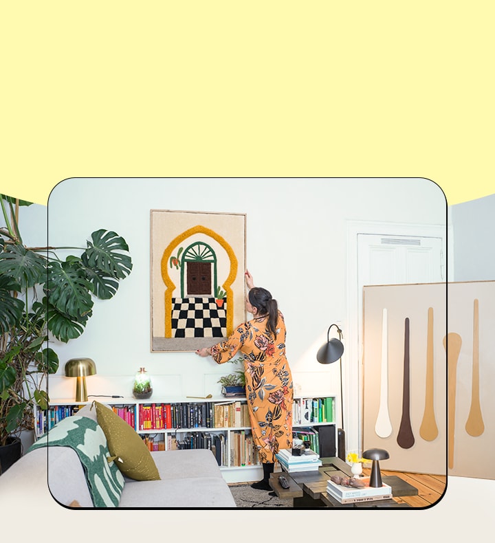 It's an image of a woman hanging a picture on the wall.