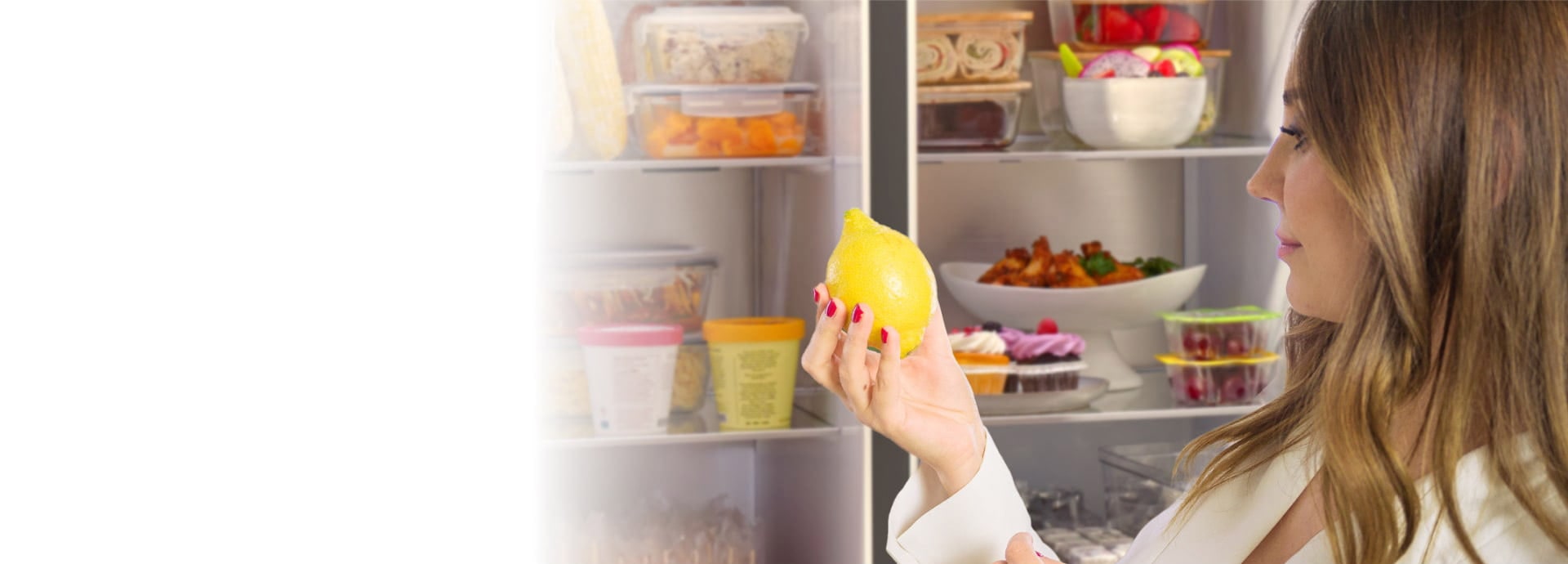 A woman taking out a lemon infront of the LG InstaVeiw American refrigerator door opened.