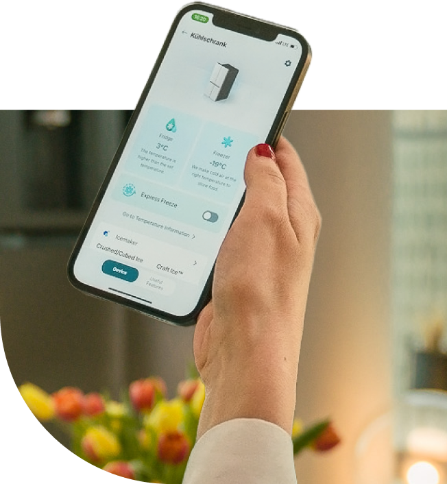 A woman holding her phone with LG ThinQ app opended to adjust the temperature of the LG InstaView American refrigerator.