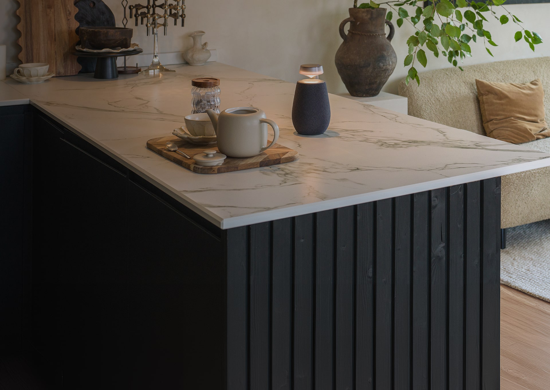 An LG Xboom XO2T wireless speaker with its Mood Lighting feature turned on is placed in front of a tea set on the dining bar.